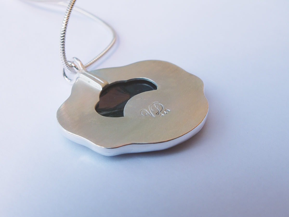 Gold pendant with a heart cutout on a white background