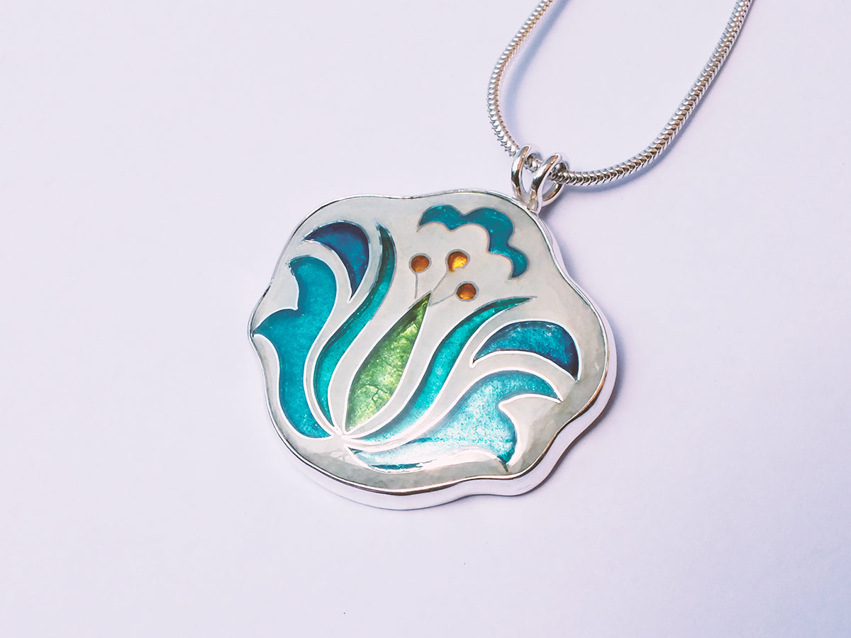 Silver pendant with floral design on a light purple background