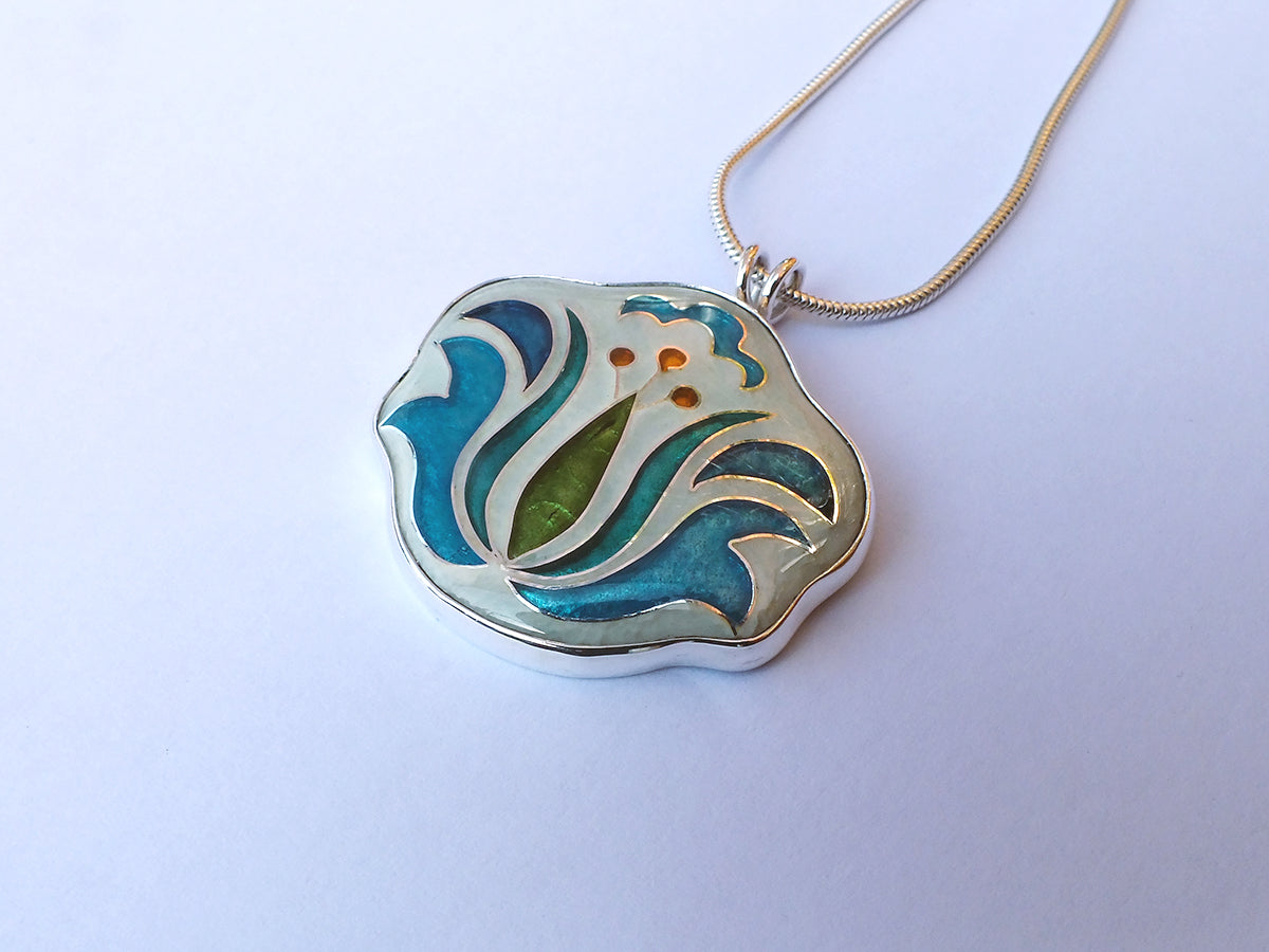 Decorative pendant necklace with blue and green design on a white background
