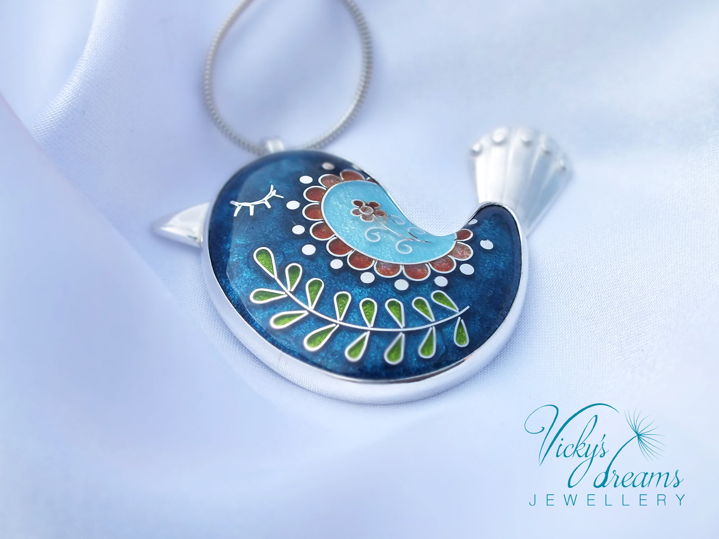Decorative pendant with blue and silver design on a light blue background, branded 'Vicky's Dreams Jewellery'.
