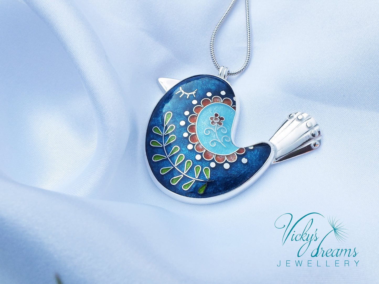 Decorative pendant with floral design on a light blue background, featuring 'Vicky's Dreams Jewellery' logo.