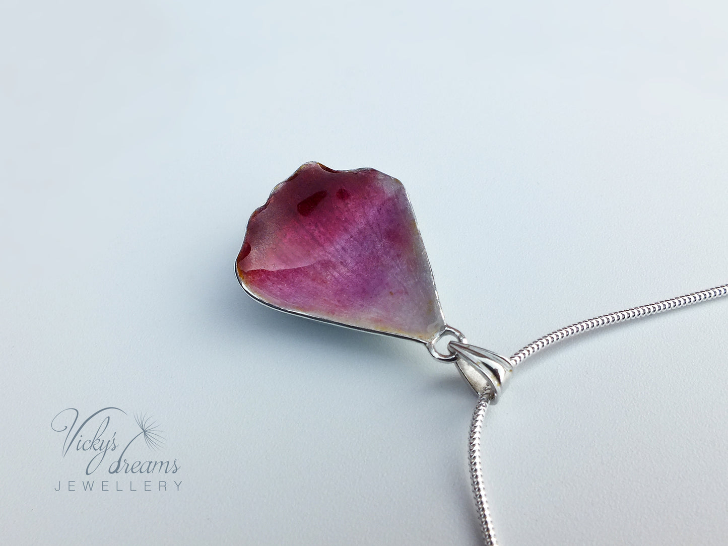 Pink flower petal pendant worn on sterling silver necklace