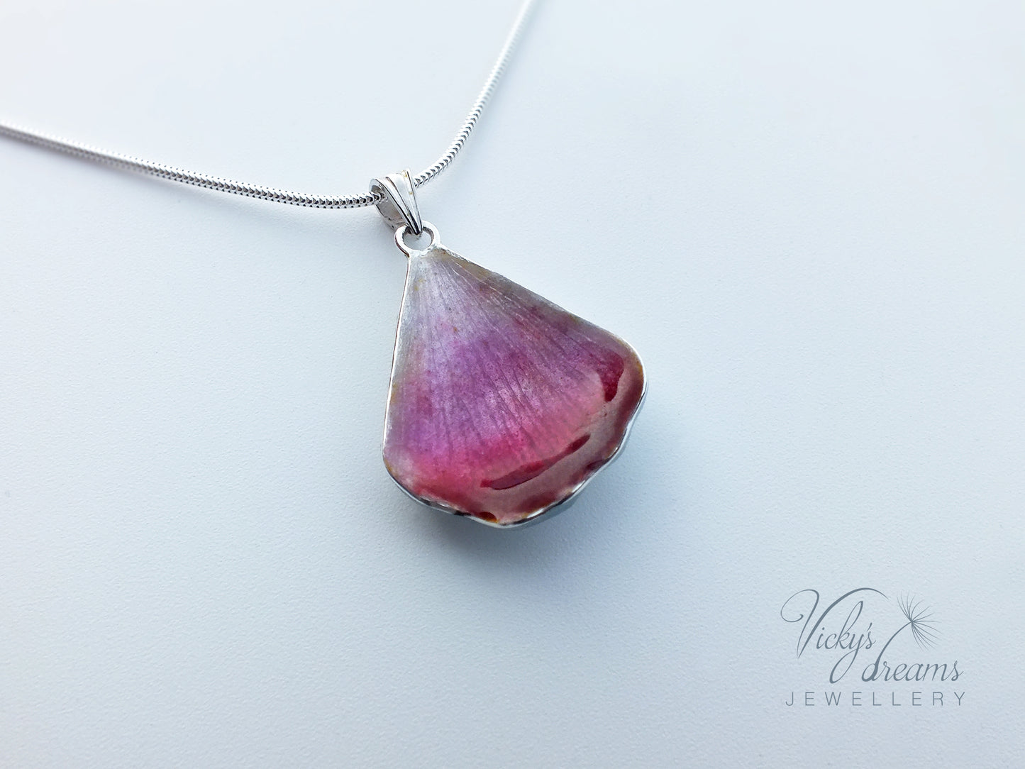 Pink flower petal pendant worn on sterling silver necklace
