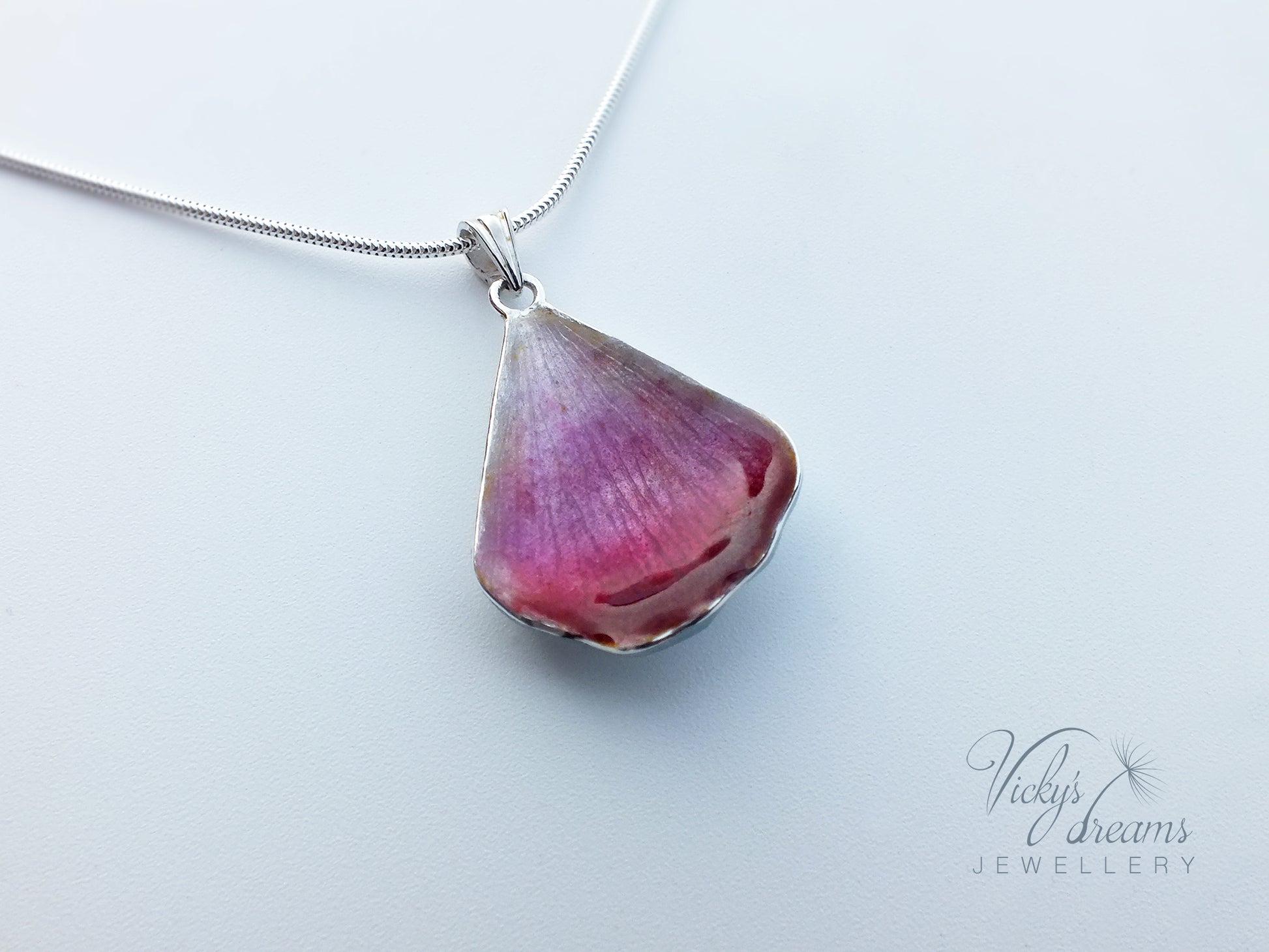 Pink flower petal pendant worn on sterling silver necklace