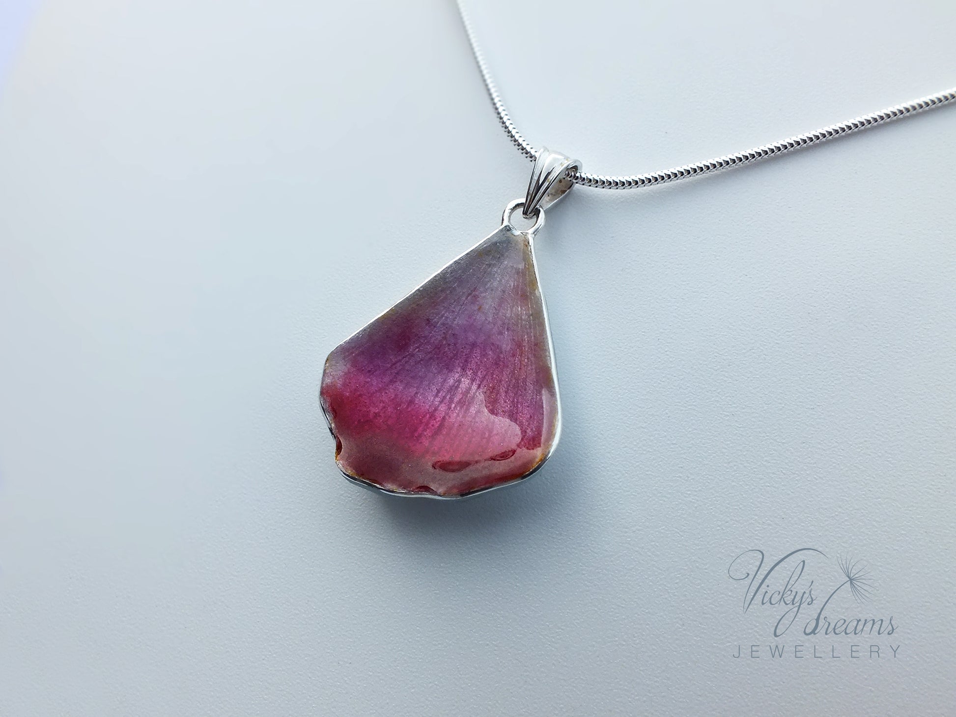 Pink flower petal pendant worn on sterling silver necklace