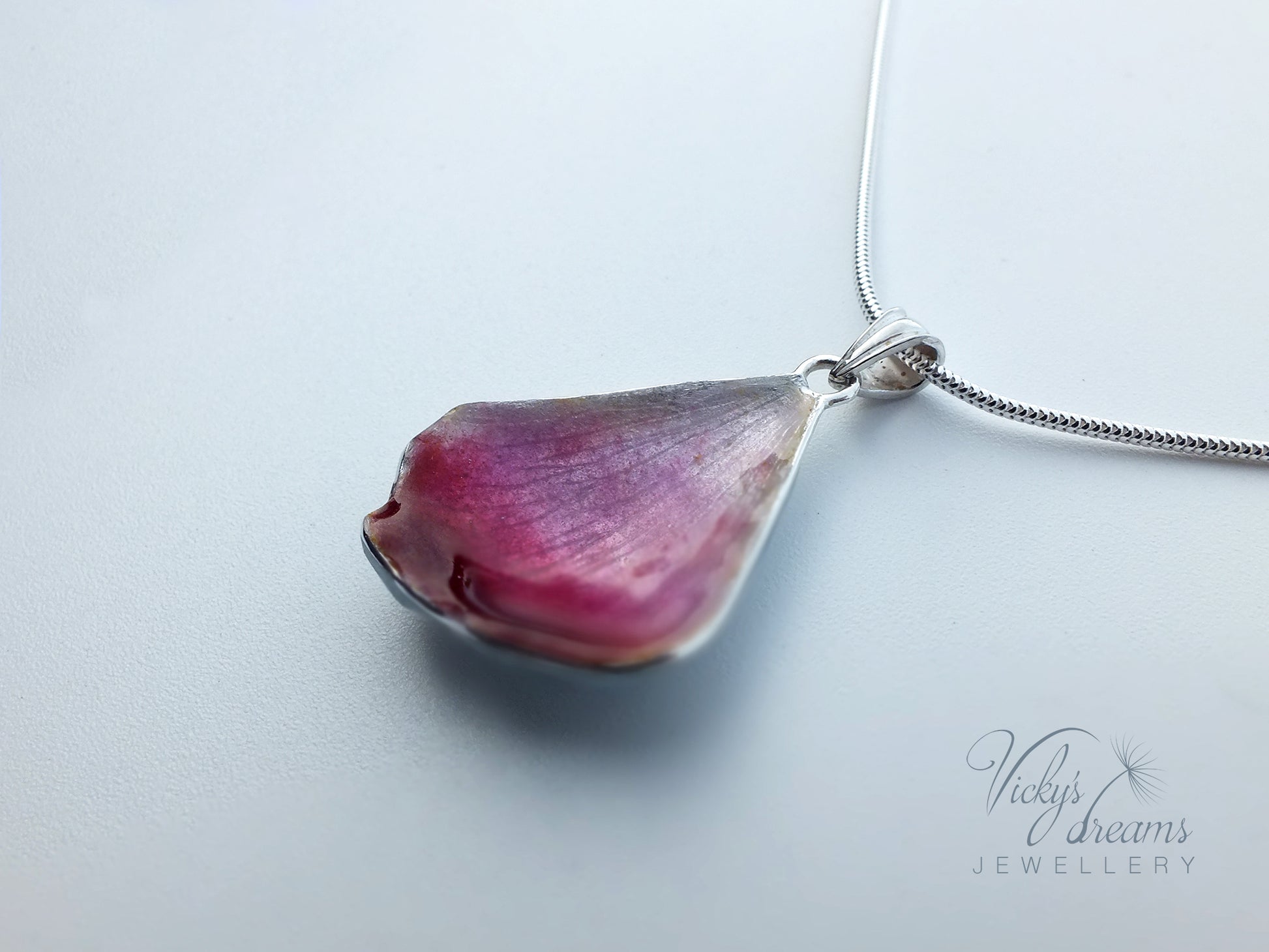 Pink flower petal pendant worn on sterling silver necklace