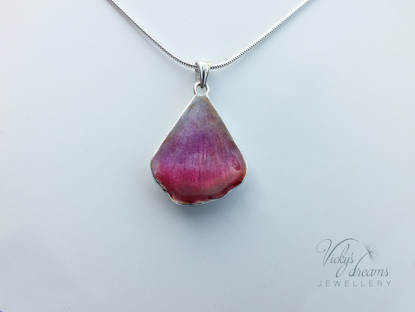 Pink flower petal pendant worn on sterling silver necklace