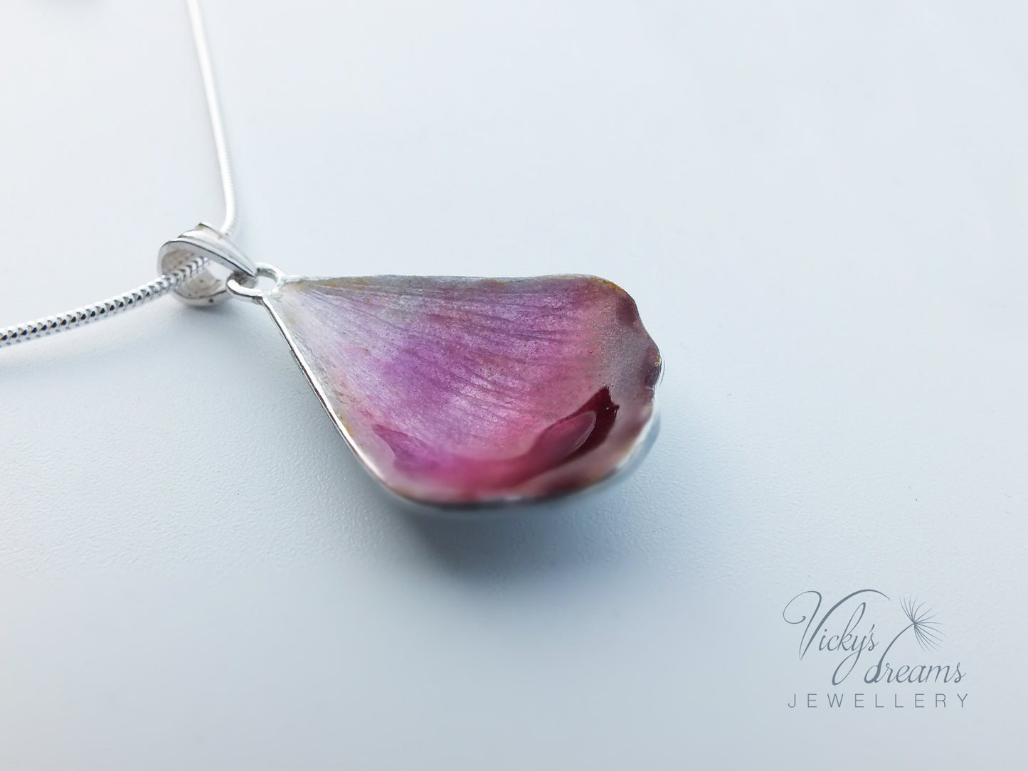 Pink flower petal pendant worn on sterling silver necklace