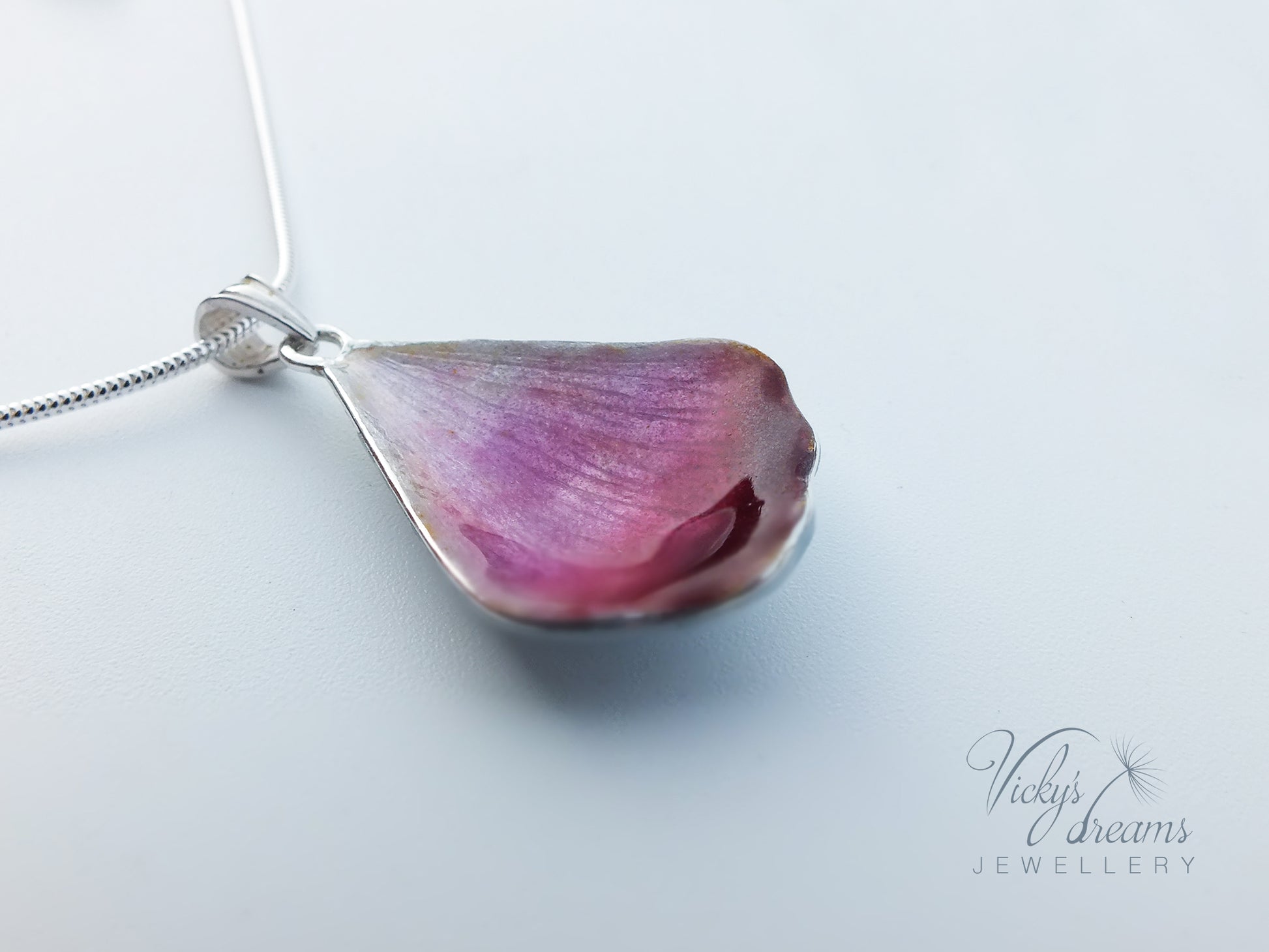 Pink flower petal pendant worn on sterling silver necklace