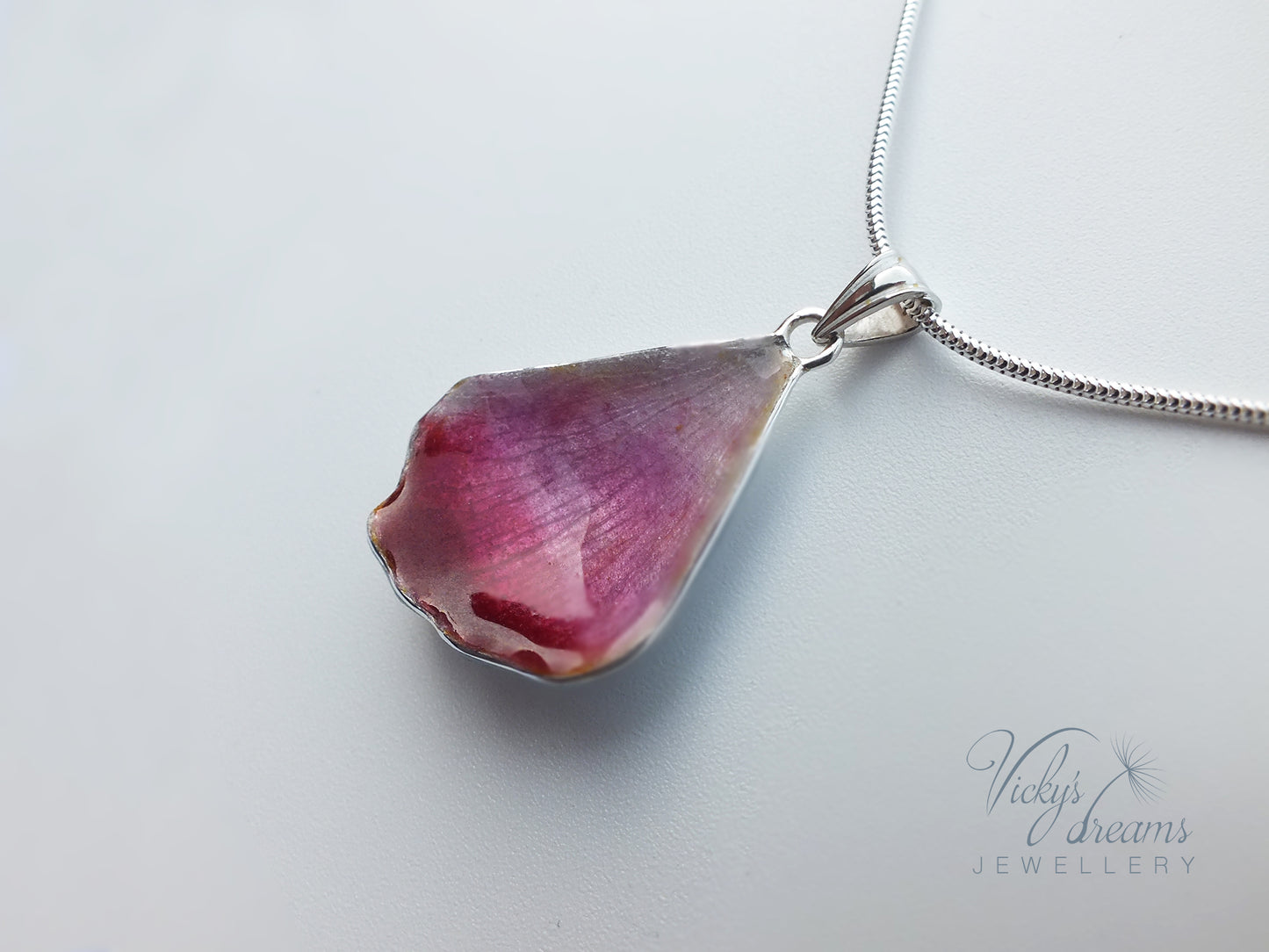 Pink flower petal pendant worn on sterling silver necklace