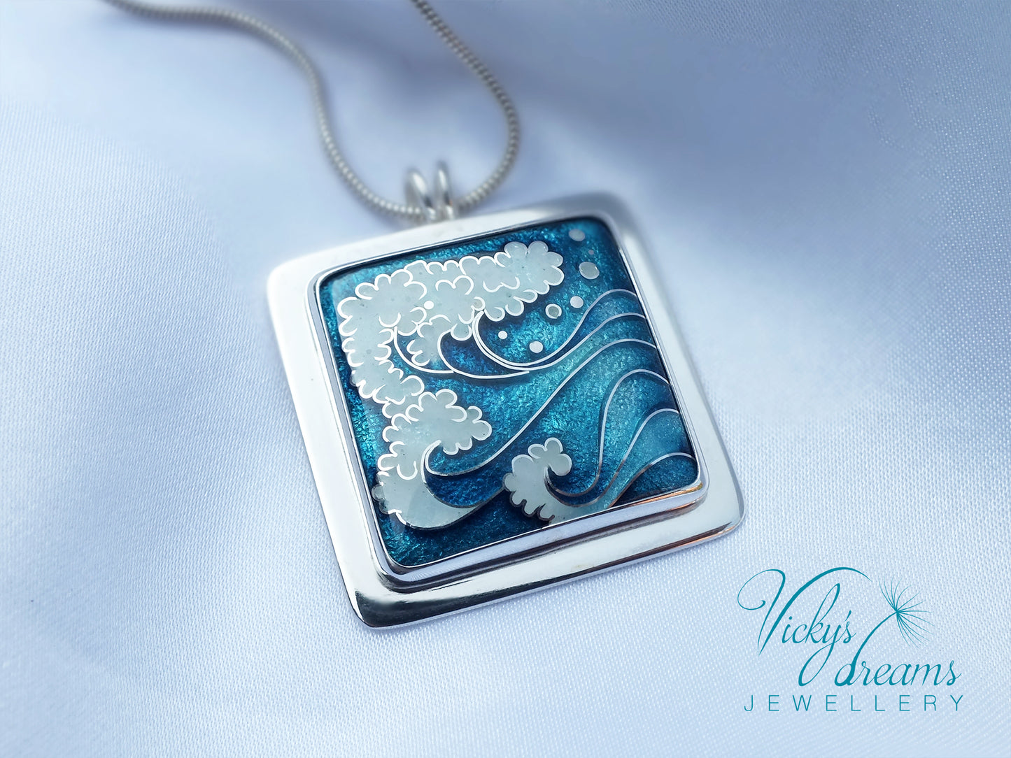 Silver pendant with floral design on a light blue background, featuring 'Vicky's Dreams Jewellery'.