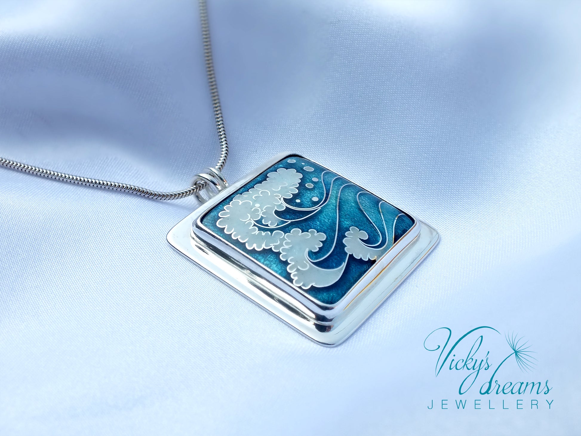 Jewelry pendant with blue and white design on a light blue background, featuring 'Vicky's Dreams Jewellery' logo.