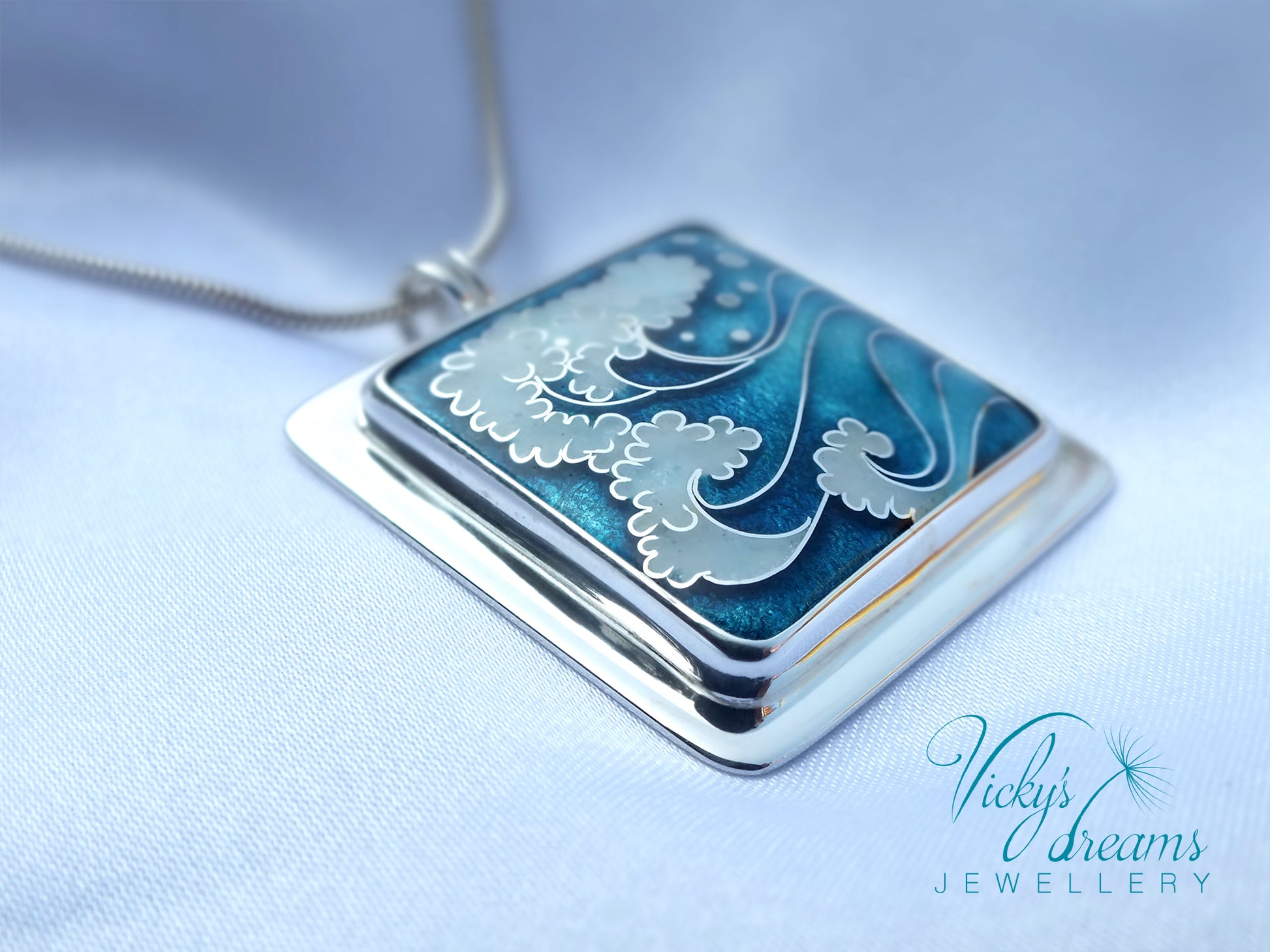 Silver pendant with blue and white design on a light blue background, branded 'Vicky's Dreams Jewellery'.