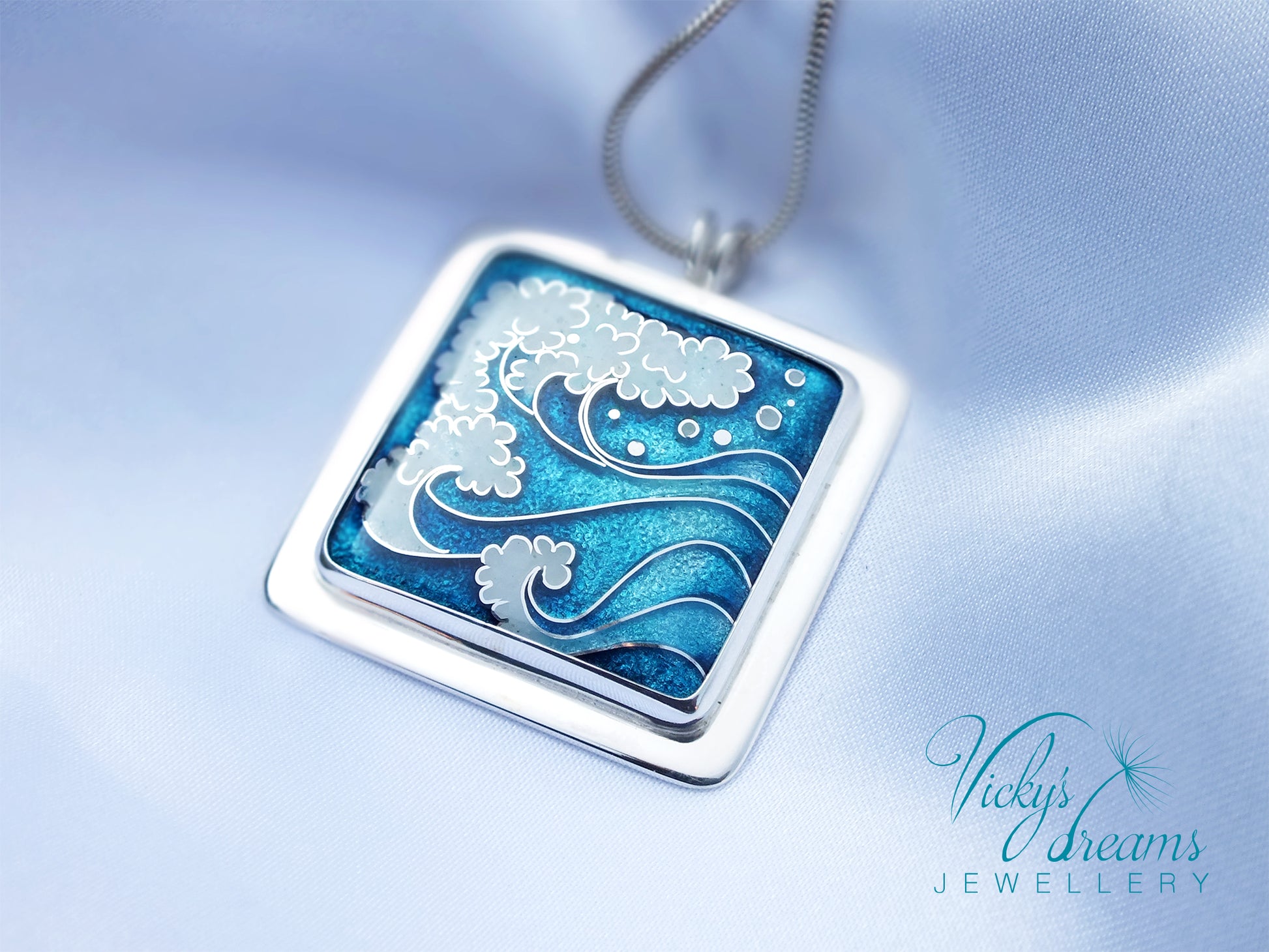 Silver pendant with blue and white wave design on a light blue background, branded 'Vicky's Dreams Jewellery'.