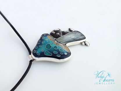 Butterfly-shaped pendant with blue and green pattern on a white background