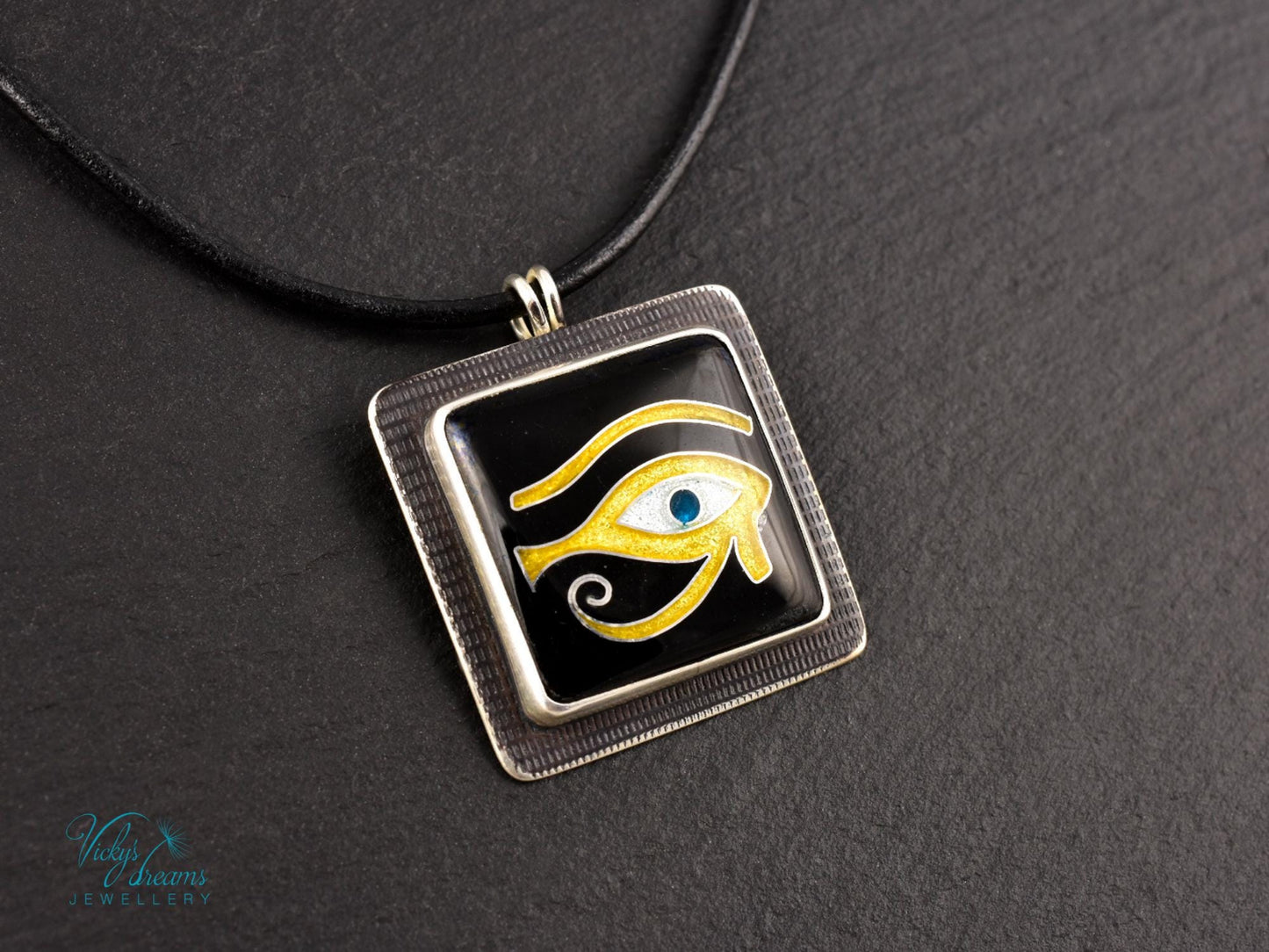 Handmade Egyptian cloisonné enamel Horus Eye pendant in black, gold, and blue set in oxidised sterling silver