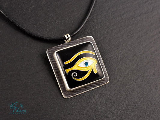 Handmade Egyptian cloisonné enamel Horus Eye pendant in black, gold, and blue set in oxidised sterling silver
