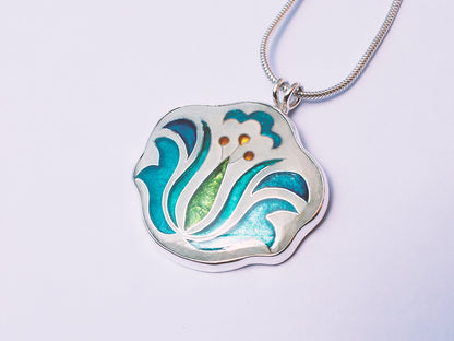 Silver pendant with floral design on a light purple background