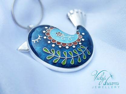 Decorative pendant with intricate designs on a blue background, featuring the brand 'Vicky's Dreams Jewellery'.