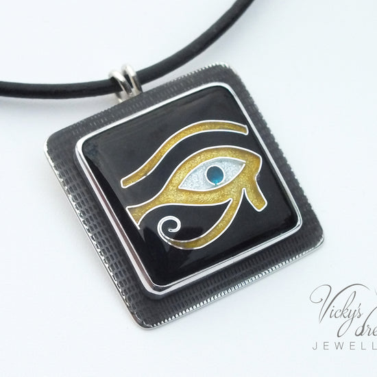 Handmade Egyptian cloisonné enamel Horus Eye pendant in black, gold, and blue set in oxidised sterling silver