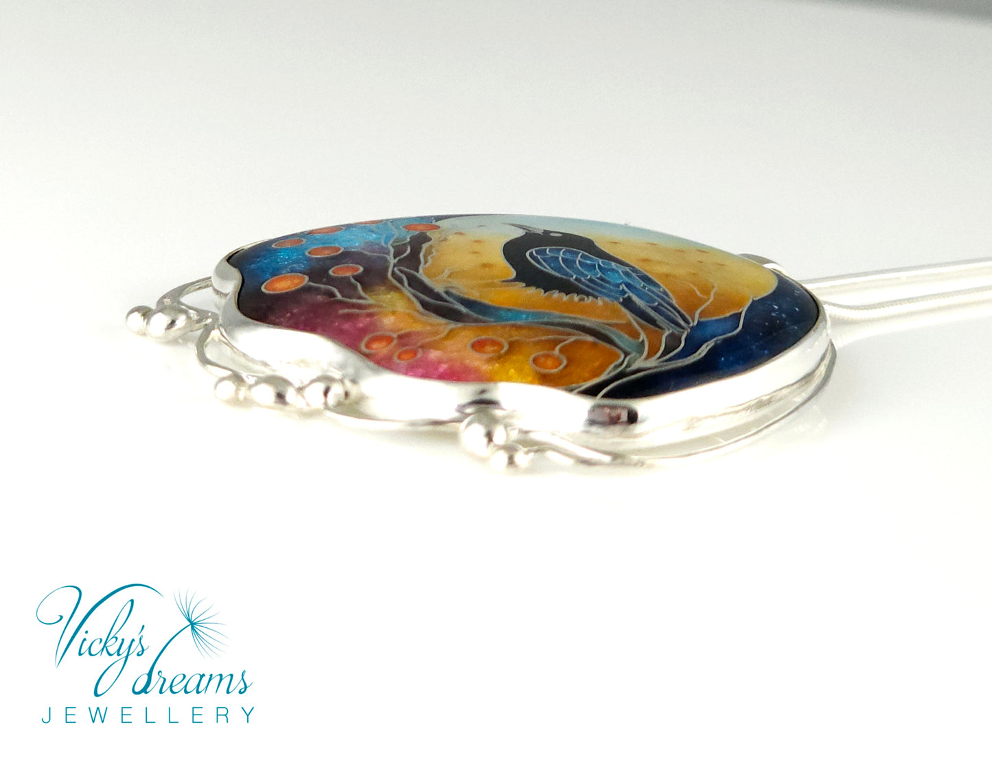 Handmade sterling silver cloisonné enamel pendant featuring a raven with red berries, vibrant blues and golden tones, nature-inspired jewellery