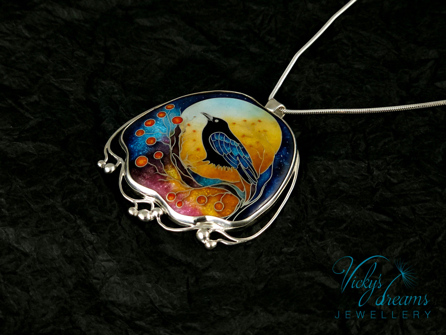 Handmade sterling silver cloisonné enamel pendant featuring a raven with red berries, vibrant blues and golden tones, nature-inspired jewellery