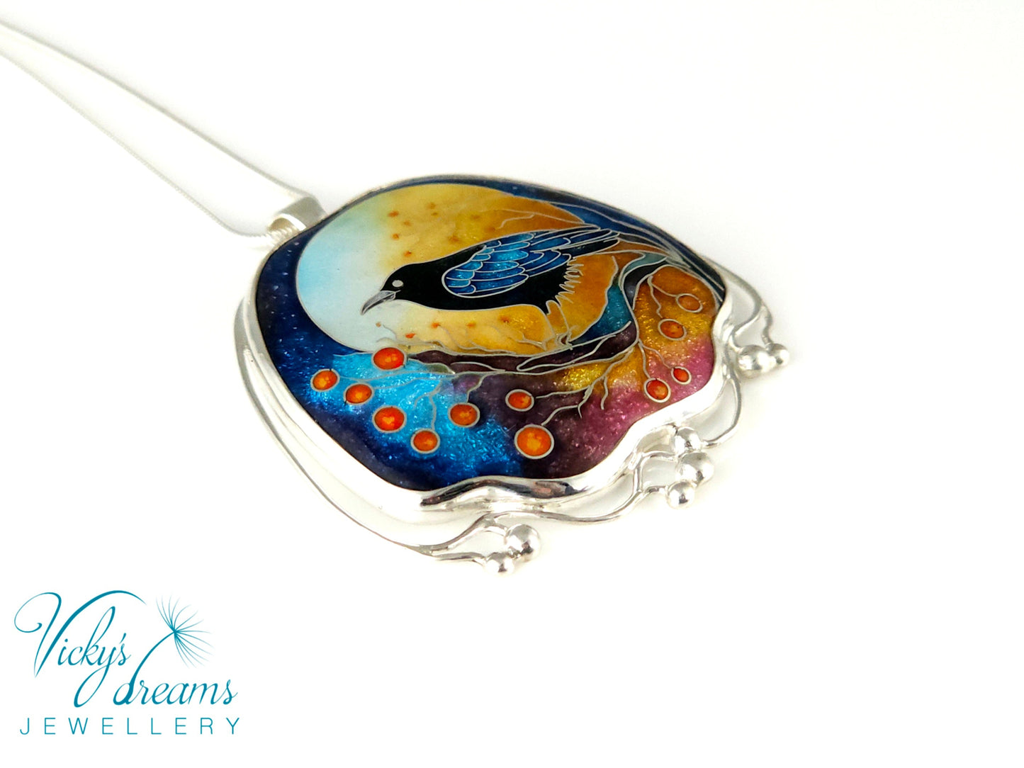 Handmade sterling silver cloisonné enamel pendant featuring a raven with red berries, vibrant blues and golden tones, nature-inspired jewellery