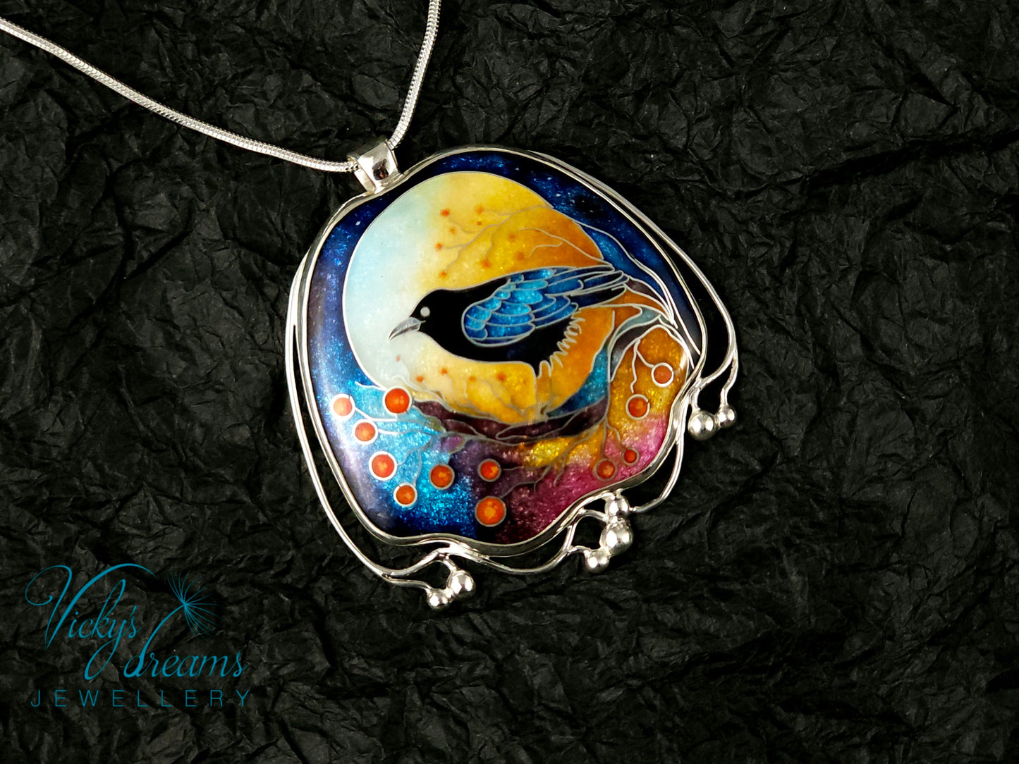 Handmade sterling silver cloisonné enamel pendant featuring a raven with red berries, vibrant blues and golden tones, nature-inspired jewellery