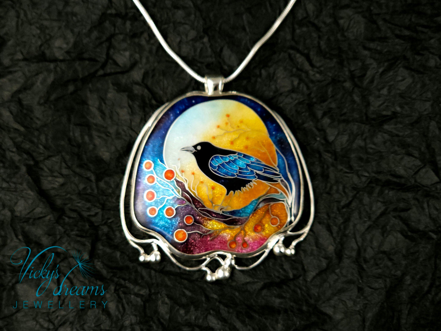 Handmade sterling silver cloisonné enamel pendant featuring a raven with red berries, vibrant blues and golden tones, nature-inspired jewellery