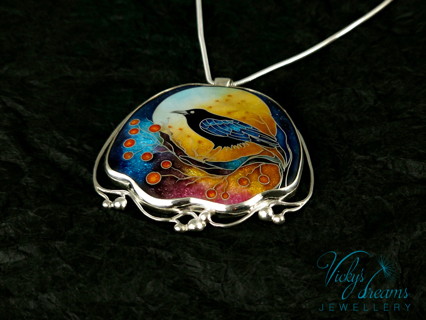Handmade sterling silver cloisonné enamel pendant featuring a raven with red berries, vibrant blues and golden tones, nature-inspired jewellery